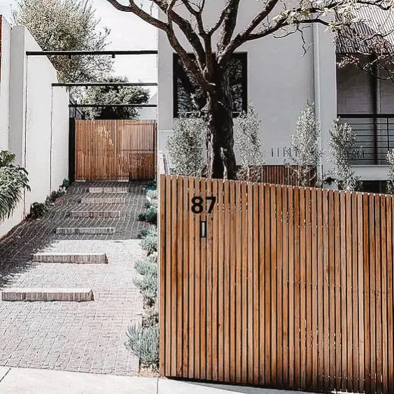 Clôture en bois moderne devant une maison avec une allée pavée.