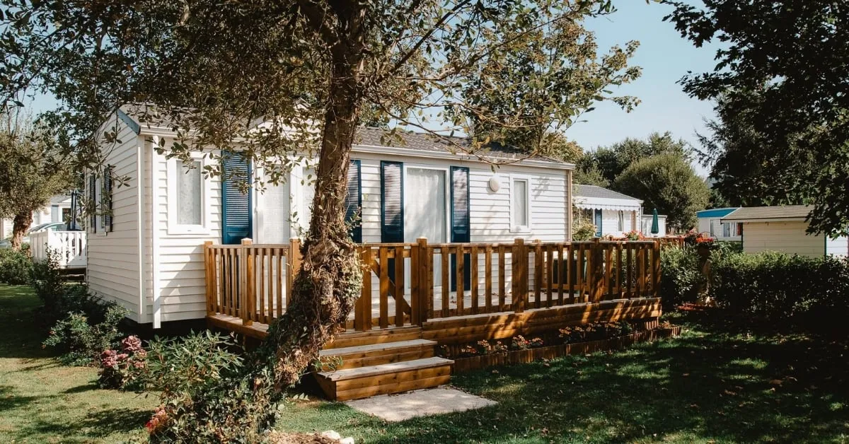 Une maison mobile confortable entourée de verdure, avec un espace extérieur en bois qui améliore son attrait accueillant.