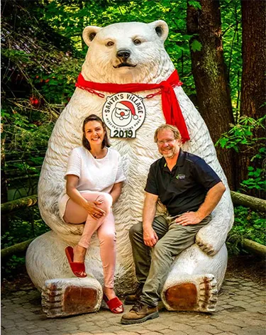 Professeur Rob et une invitée posant avec une statue d'ours polaire à Santa's Village