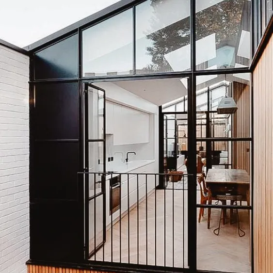 Extension de maison moderne avec des portes vitrées et un espace cuisine-salle à manger ouvert.