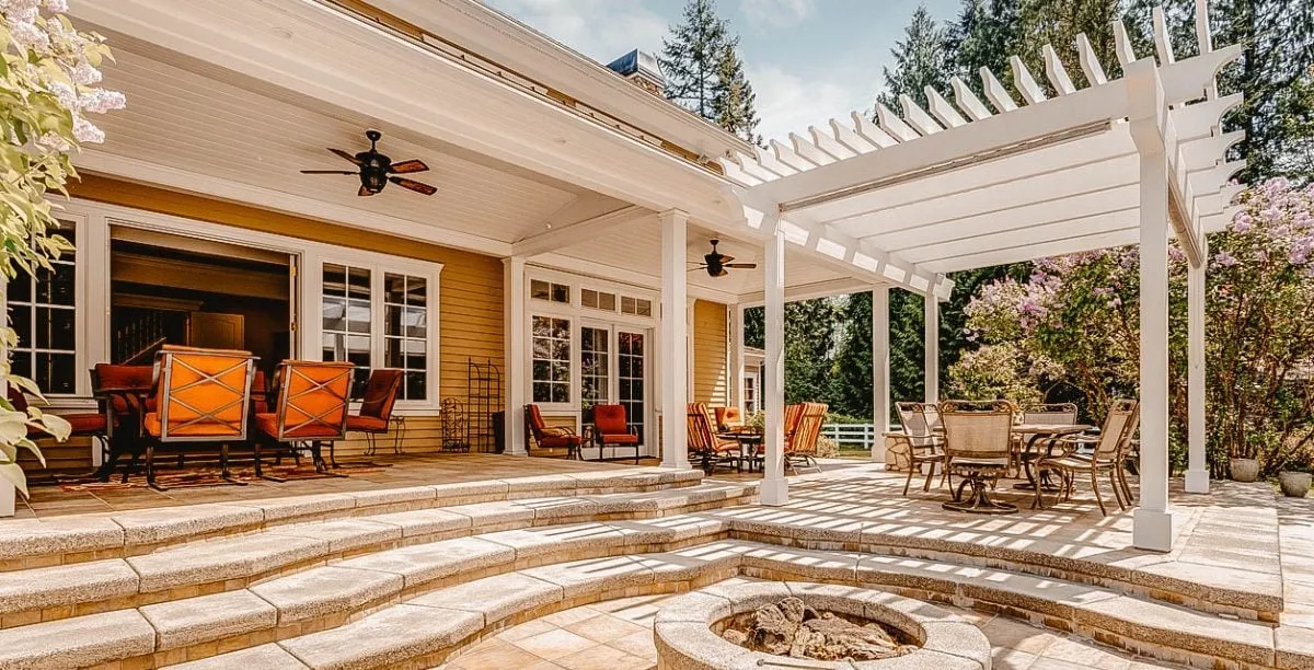 Terrasse spacieuse avec pergola blanche et coin salon extérieur.