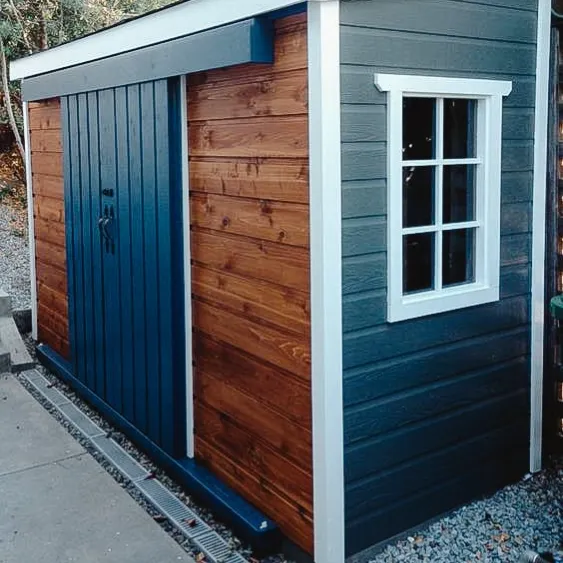 Abri compact et élégant avec un extérieur en bois et bleu, doté d'une petite fenêtre.