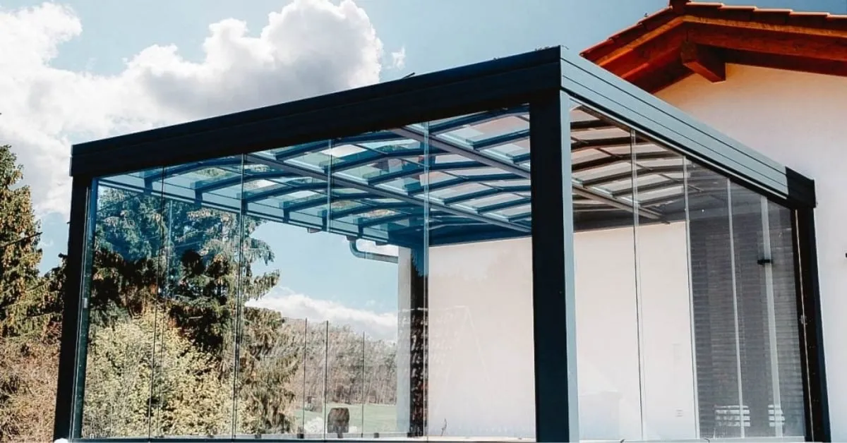 Solarium moderne avec des murs en verre et une structure noire élégante.