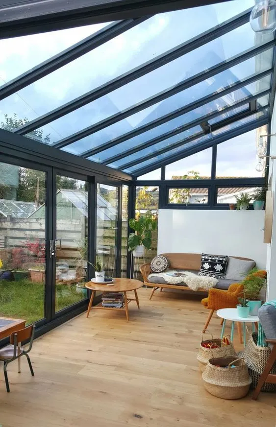 Bright and airy sunroom with a glass roof, Scandinavian-style furniture, and a view of the garden.