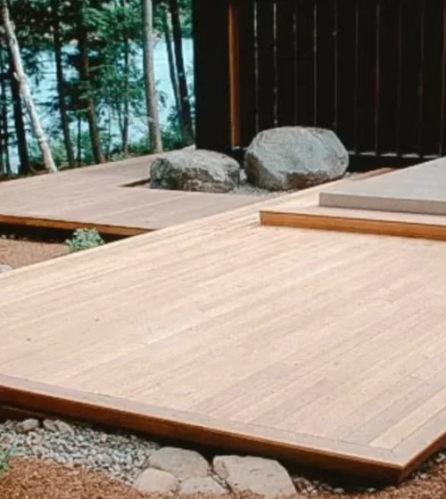 Terrasse basse en bois au bord de l'eau, entourée de nature