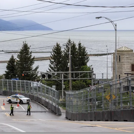 Vue sur la route sécurisée avec des clôtures de sécurité et des policiers, à proximité d'une zone côtière.