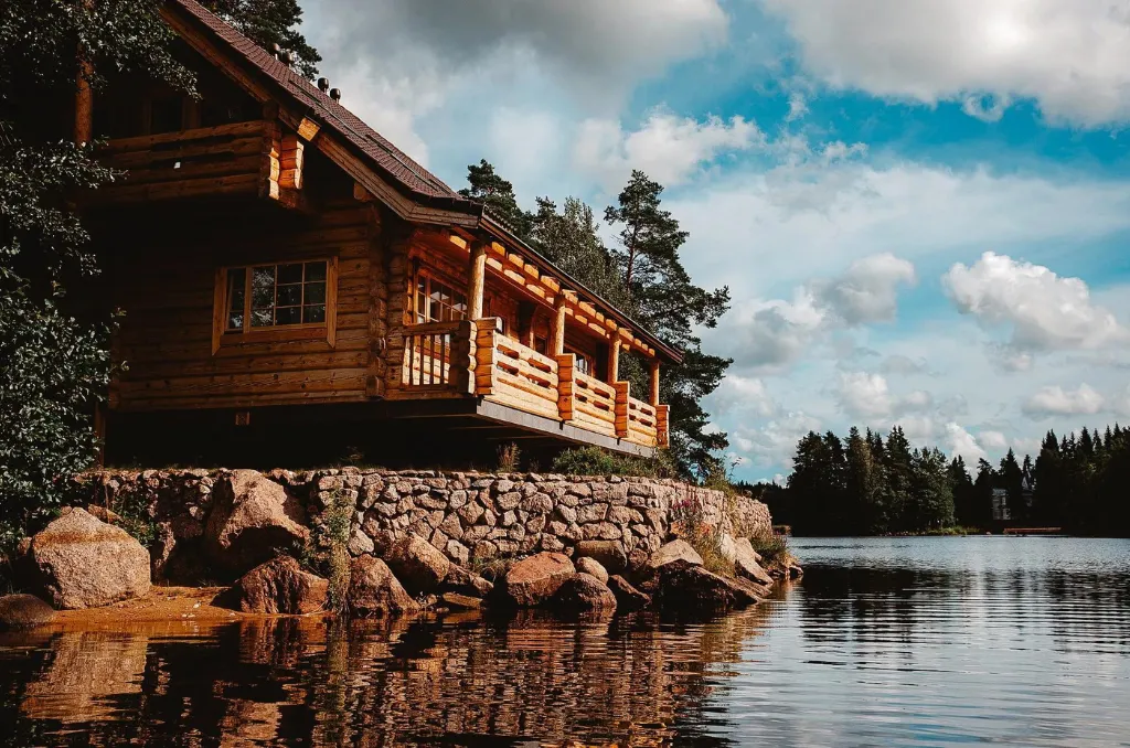 Chalet en bois construit sur une berge rocheuse, surplombant un lac tranquille