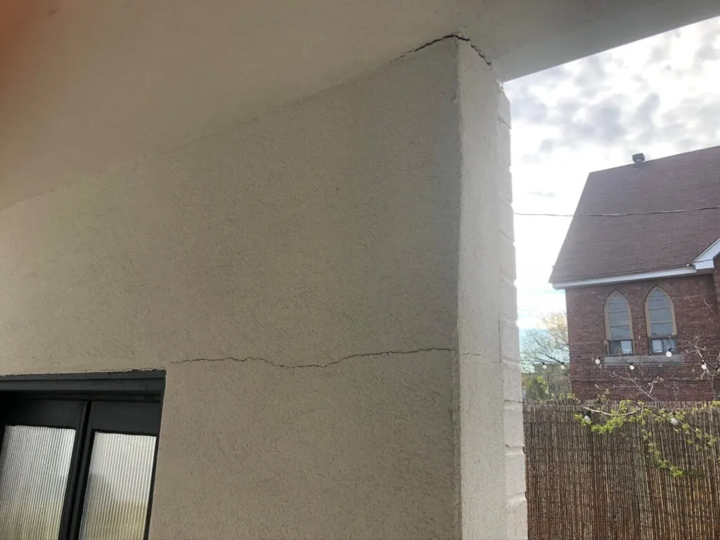 Fissure visible sur un mur extérieur d'une maison, indiquant un affaissement ou un problème structurel potentiel.