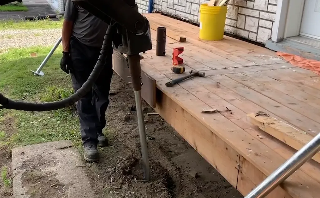 Installation d'un pieu vissé sous une structure en bois existante.