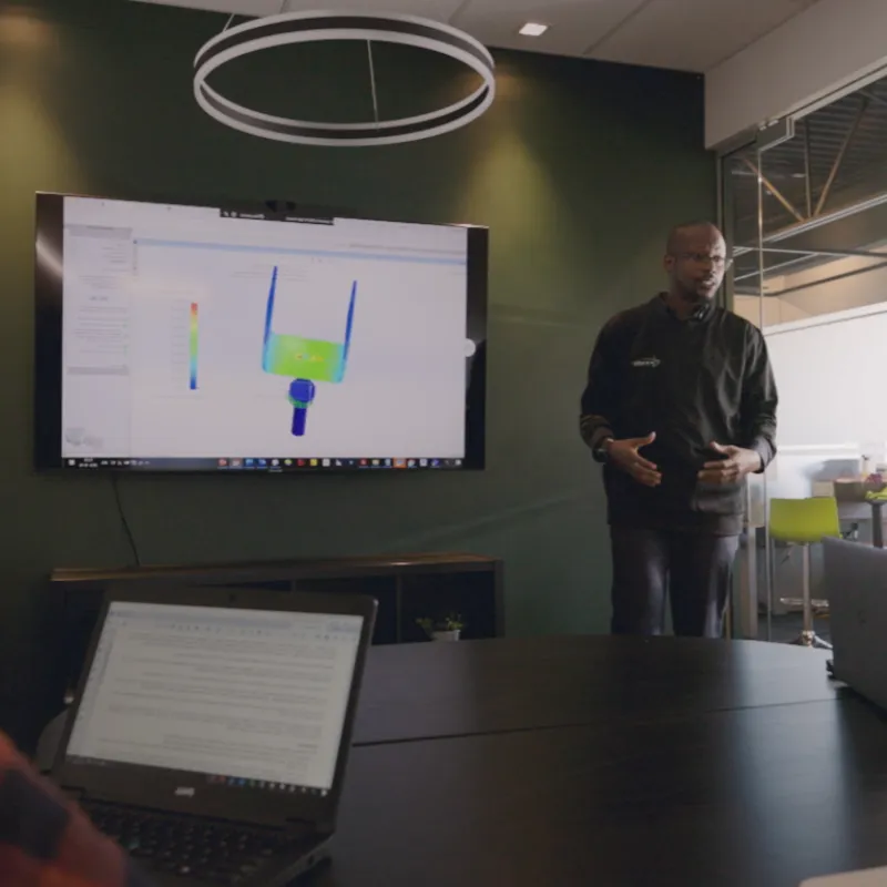 Ingénieur en train de présenter un projet technique sur un écran dans une salle de réunion.