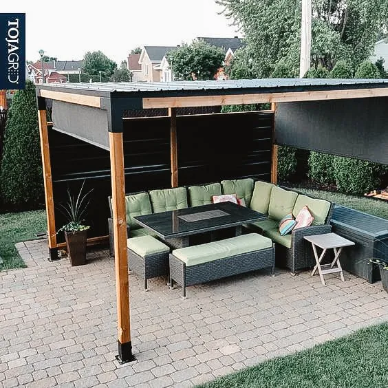 Pergola moderne avec un espace de détente extérieur confortable, comprenant des coussins verts et une table, construite sur une terrasse en briques.